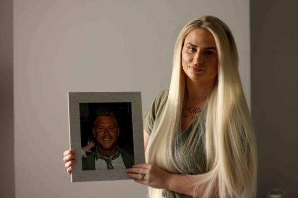 Samantha Morris smiles holding a photo of her former husband 