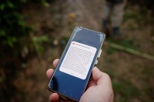 A person holds a mobile phone showing an a<em></em>lert that announces traffic restrictions in 20 municipalities affected by the overflowing of the Poyo wadi and the Magro river due to the DANA, in Quart de Poblet, Valencia, Spain, November 13, 2024. REUTERS/Eva Manez