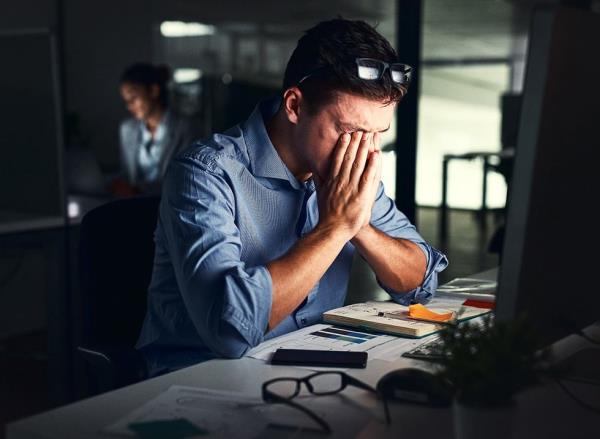 A tired man working at his desk in the office late at night