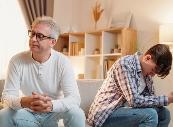 A father and son with their backs to each other after an argument