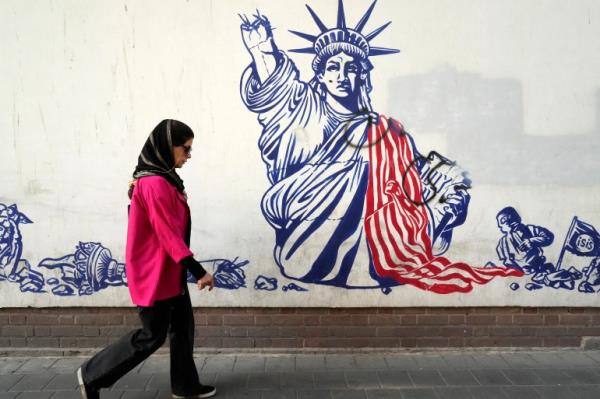 A woman walks past an anti-American mural on the wall of the former U.S Embassy in Tehran, Iran