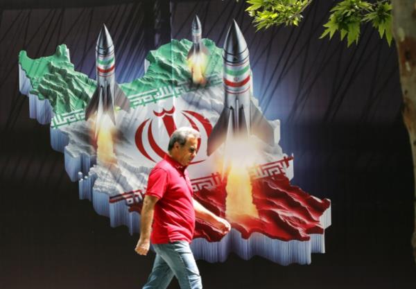 An Iranian man walks past a huge anti-Israeli banner