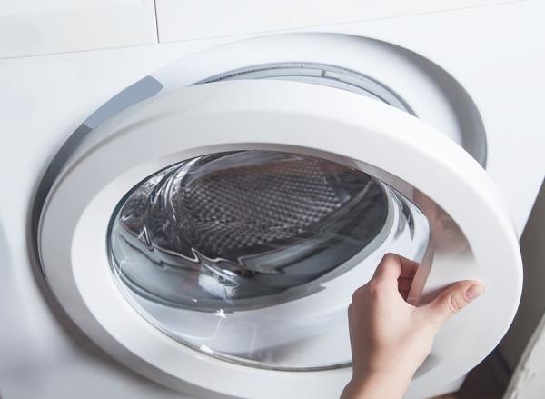 A woman opens the door of a dryer