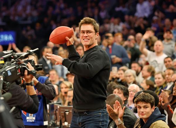 NFL great Tom Brady autographs and throws a football into the stands from celebrity row in the first half at Madison Square Garden.