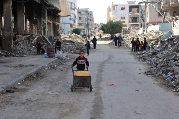 A young boy pushes a cart of water.